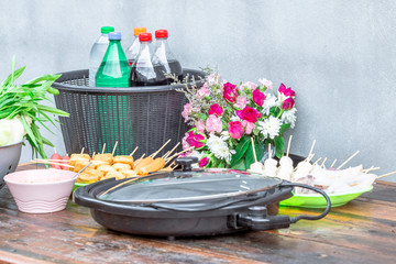 Close-up view of food sets (vegetables, meatballs, electric stoves, beverages) placed on the table for use in the hot pot seasoning or soup.