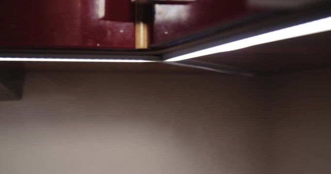 Close up slow motion shot, led lights in kitchen with steam from boiling water kettle, 4K.