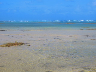 La mer calme, avec des vagues au loin, sous le ciel bleu