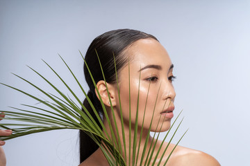 Fototapeta premium Sexy Asian lady looking at camera with tropical leaf