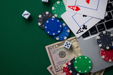 Gaming onlan business, online casino or casino. Green gaming table, laptop, money and chips. Game concept for design.