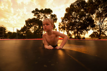 Little boy playing on trampoline at sunset © Caseyjadew