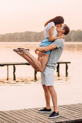 Loving young couple hugging on pier at sunset in summer.