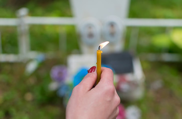 The flame of a wax candle in the hand of a people in the cemetery