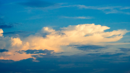 Blue summer sky with cumulus clouds in the rays of the setting sun