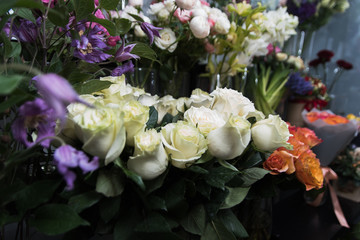 Showcase with vases with different colored roses, tulips, peonies in flower shop. Beautiful spring bouquets. Small family business. Work florist