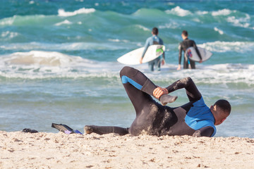 A surfer does a warm-up on the background of the sea on a sandy beach