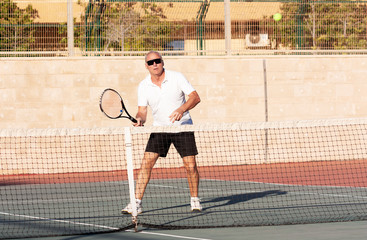 Senior man playing tennis on an outdoor court