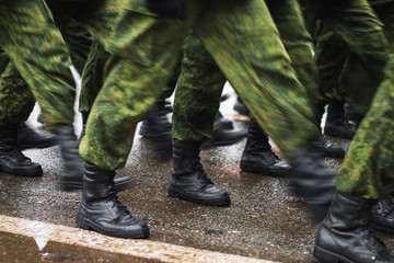 Soldier boots walking on wet asphalt during the parade of memory. The military marching down the street. Many shoes and camouflage clothing. Motion lubrication.