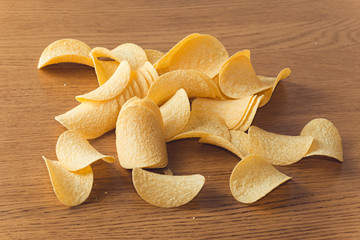 Delicious potato chips, laying on wooden table background