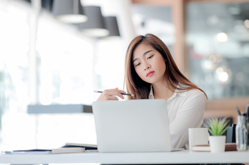Young pretty designer working with laptop while sitting at office desk in modern office.