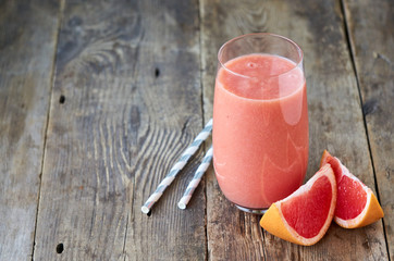 Glass of grapefruit smoothie on a wooden background