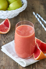 Glass of grapefruit smoothie on a wooden background