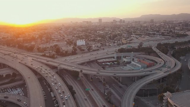 Aerial Drone View Panning Up Away from Traffic on Interstate 10 near Downtown Los Angeles California into Mountains and Hills Background as Busy Congestion Passes Through During Sunset Day