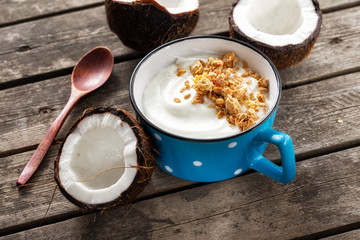 Coconut yogurt with granola in cup on wooden table. Probiotic food concept. Tasty and healthy breakfast