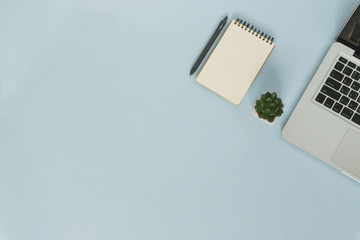Top view workspace on blue background with notebook and pen
