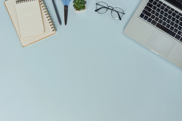 Top view workspace mockup on blue background with notebook pen and laptop.