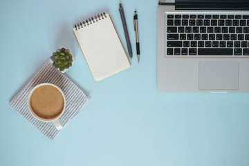 Top view workspace mockup on blue background with notebook pen and laptop.