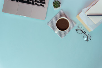 Top view workspace with  cup of coffee on a blue background