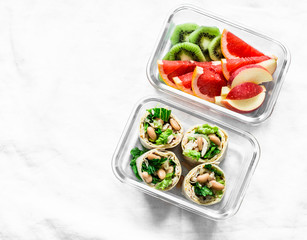 Healthy diet food lunch box - fruit and chicken, beans, green salad pita bread on a light background, top view. Sweet b savory lunch box
