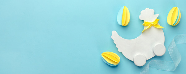 Easter holiday creative background with papercraft eggs, white wooden chicken hun on pastel blue...