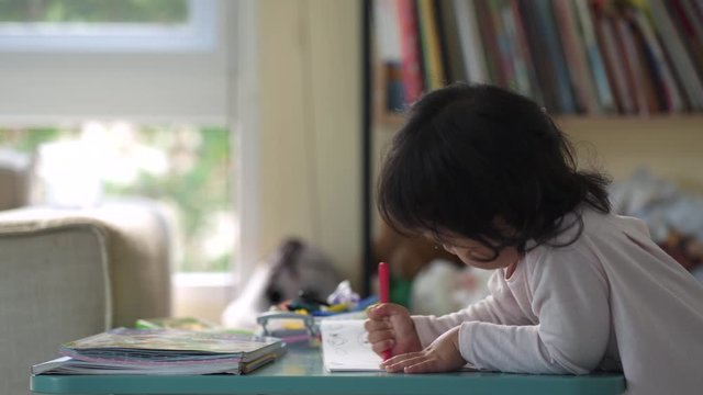 Cute little girl sitting at  her chair doing drawing picture.