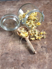 Dried flowers calendula and brewed medicinal tea on a wooden ancient table. Harvesting for the winter.