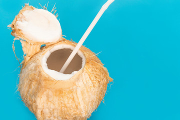 Coconut fresh milk cocktail with straw, coconut water. Summer healthy natural organic tropical exotic drink. Vacation concept on blue background. Copy space, place for text. Close up photo.