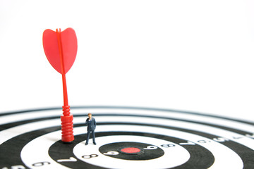 Fototapeta premium Business strategy conceptual photo - Miniature businessman with red arrow on a dartboard