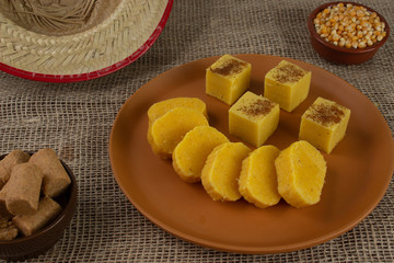 Pieces of Canjica or Curau. Tipical brazilian food made from corn. Festa Junina. In a piece of wood. with a tradicional hat.