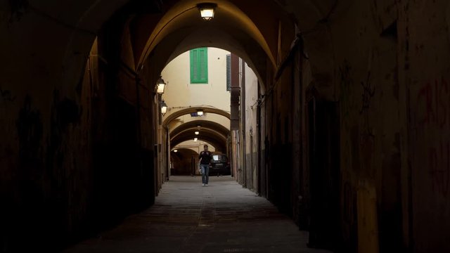Young man leaves courtyard of a house through arch in European city