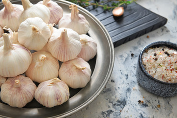 Plate with fresh garlic and spices on white background