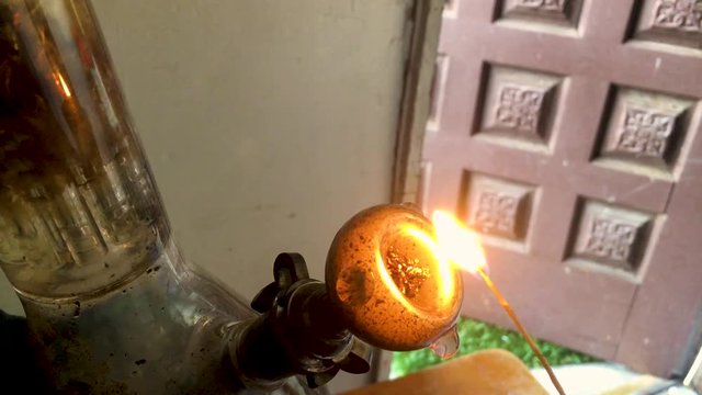 Staged bowl of Marijuana being smoked through a glass device.