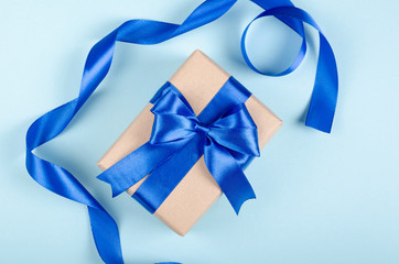 Gift box on blue background composition, present with ribbon and bow.