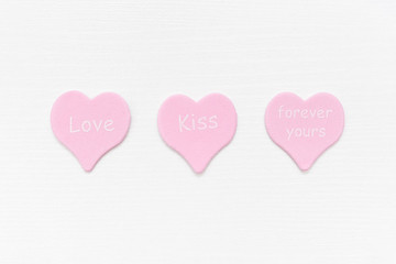 Tree pink hearts with text LOVE, KISS, FOREVER YOURS on white background with copy space. Valentines day concept. Gift for lover, love confession. Top view Flat lay Minimal style.