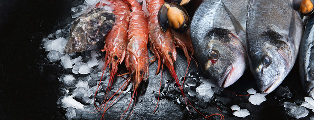 Fresh fish and seafood on black background.