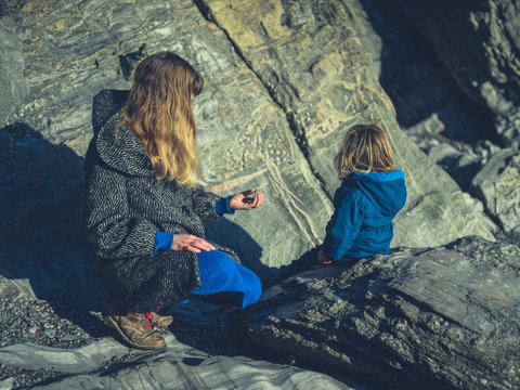 Mother sitting on rock with toddle rin winter