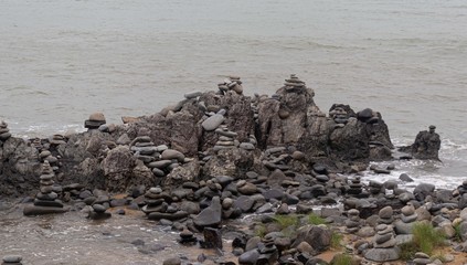 river at the edge of the dais where there are many rocks placed by people in a pile and the wave of the sea crashing.The gatz Balancing Rocks