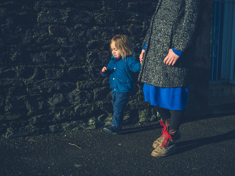 Mother And Toddler Holding Hands On Walk In Winter