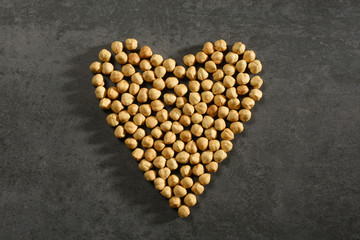 Heart shape hazelnuts on the gray stone texture with copy space, healthy eating