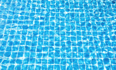 Blue water surface with bright sunlight reflections, water in swimming pool background