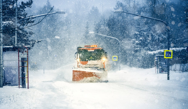Snow plow truck clearing road after winter snowstorm blizzard for car.....