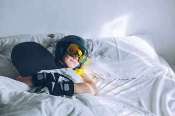 woman sleeping in bed with snowboard dreaming about ski at snow mountains