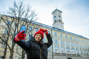 Fototapeta na wymiar woman taking selfie on her phone lviv city hall on background