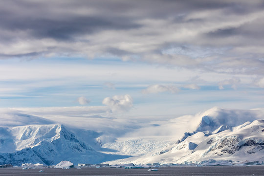 Snow and ice on the mountains near the water in Antarctica, a pristine remote environment affected by global warming and climate change