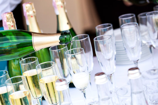 Glasses of champagne at a party or wedding celebration. The waiter pours champagne close-up.