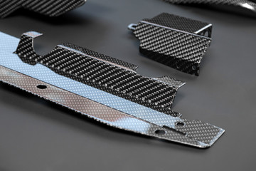 A close-up on a car exterior elements made from carbon fiber of interwoven black and gray color...