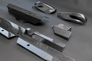 A close-up on a car exterior elements made from carbon fiber of interwoven black and gray color...