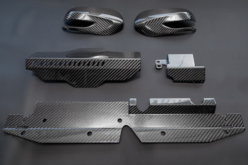 A close-up on a car exterior elements made from carbon fiber of interwoven black and gray color...