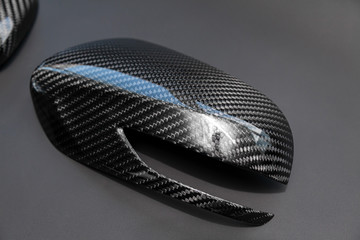 A close-up on a car exterior mirror made from carbon fiber of interwoven black and gray color from...